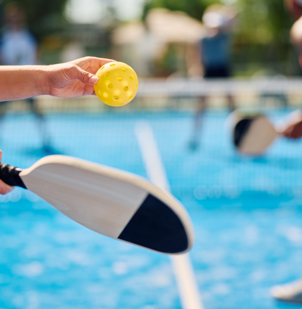 Close up of woman serving the ball while playing pickleball.